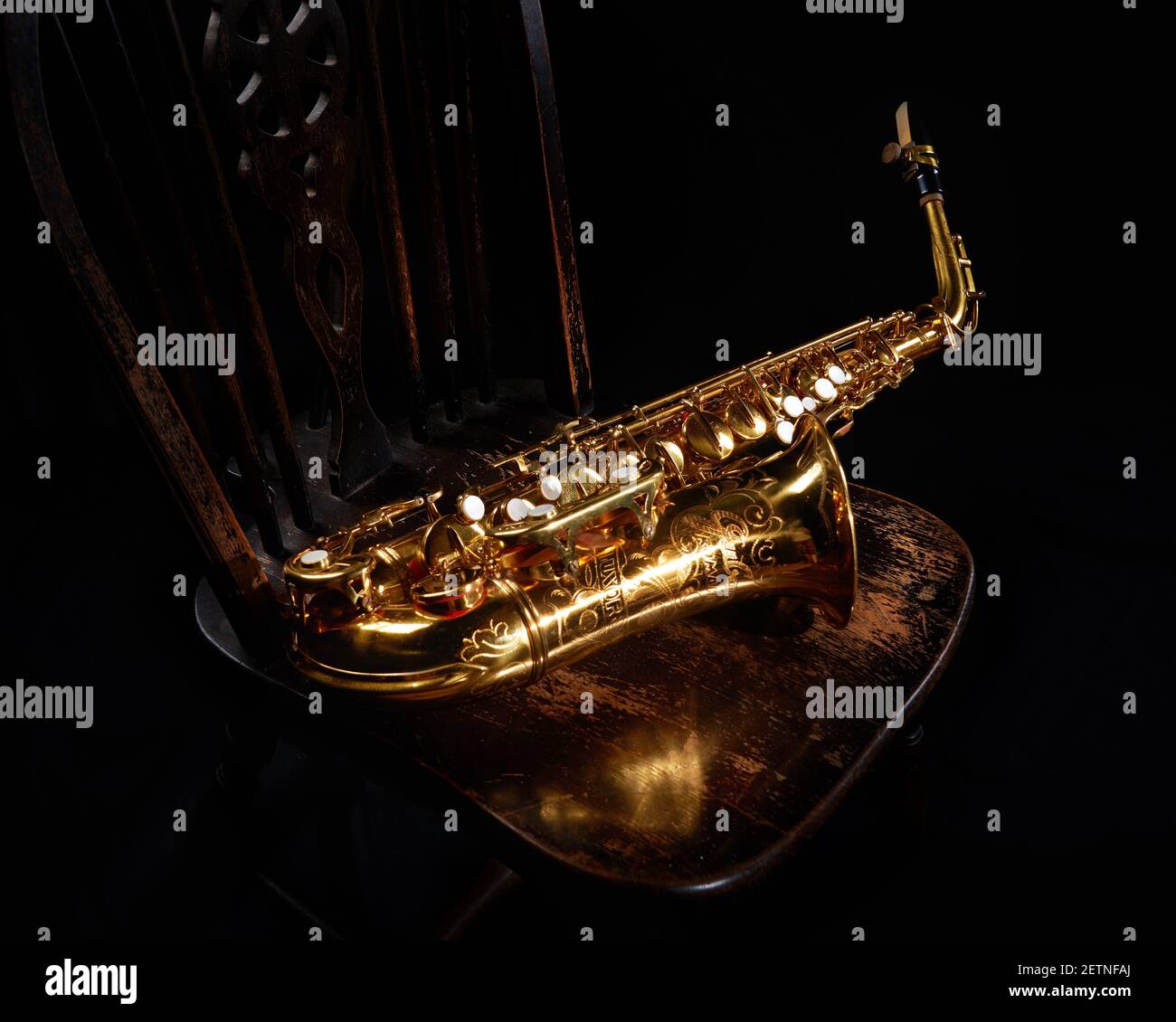 Alto Saxophone on rustic chair with reflection onto seat of chair Stock
