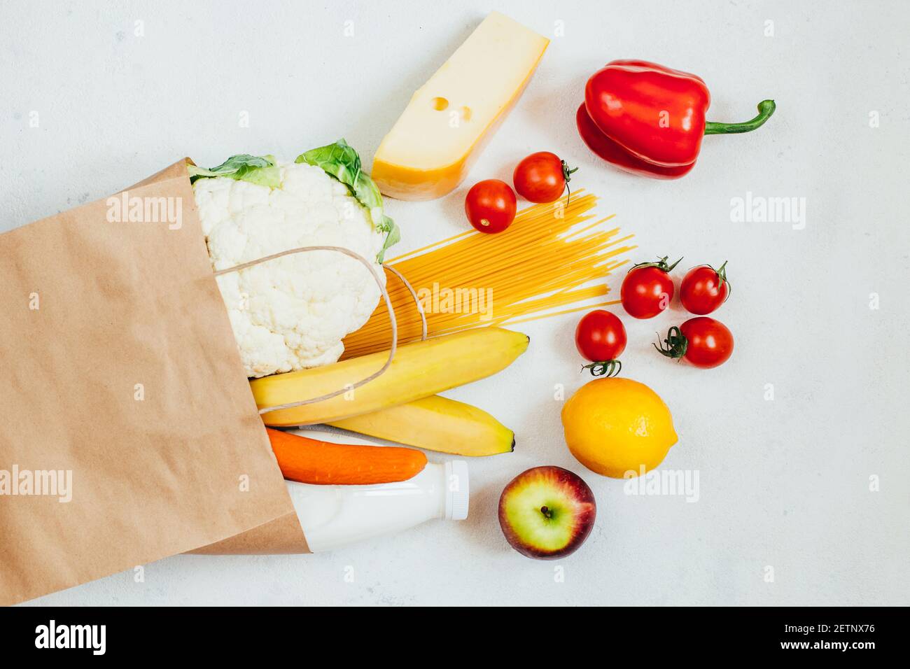 top view of paper bag with fruits, vegetables, spaghetti, cheese, milk on white background Stock Photo