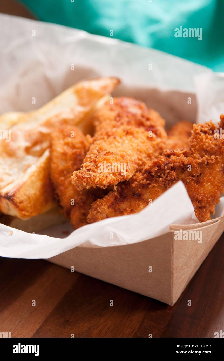 breaded chicken fingers and fries in a take out container Stock Photo