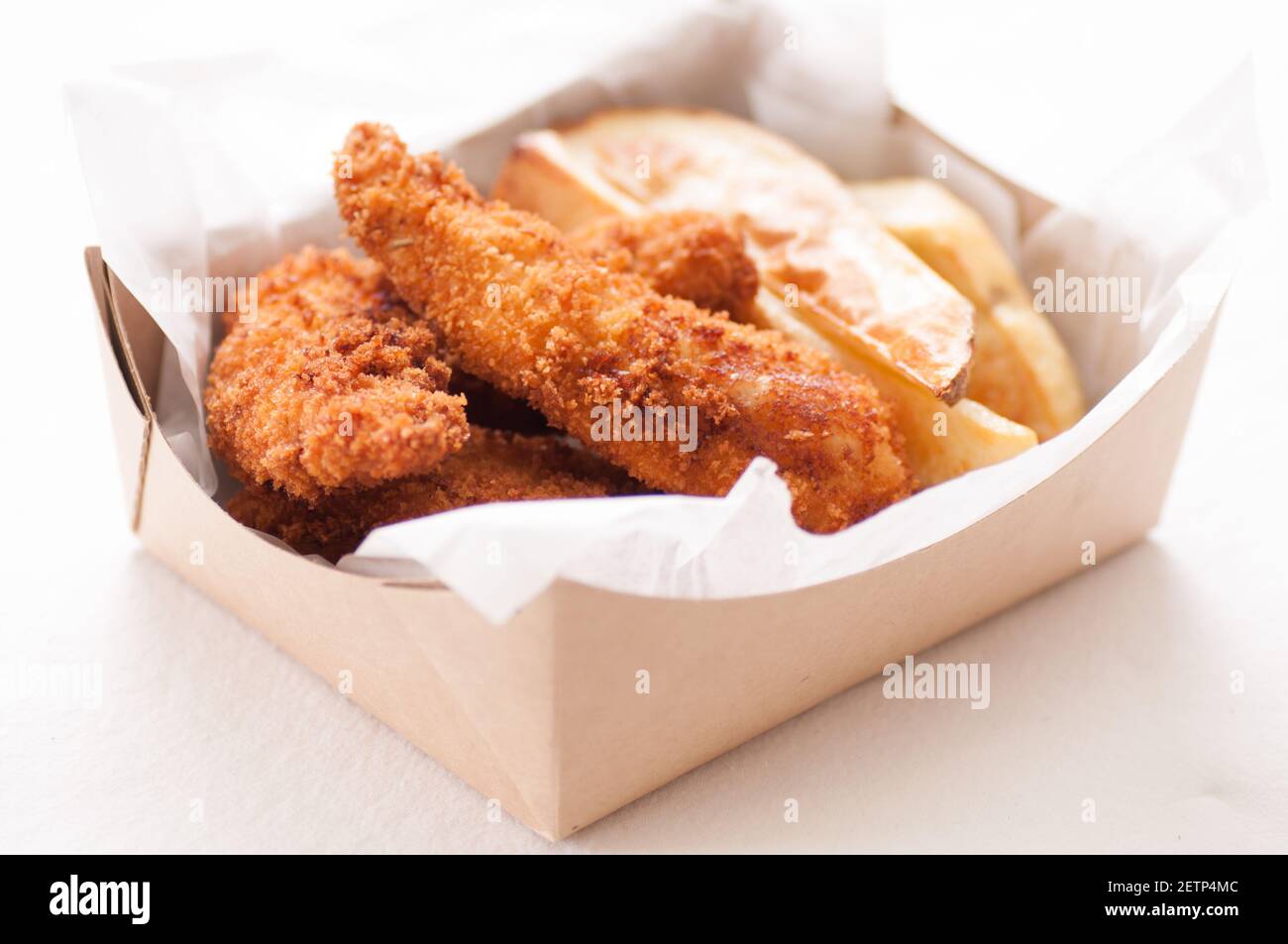 breaded chicken fingers and fries in a take out container Stock Photo