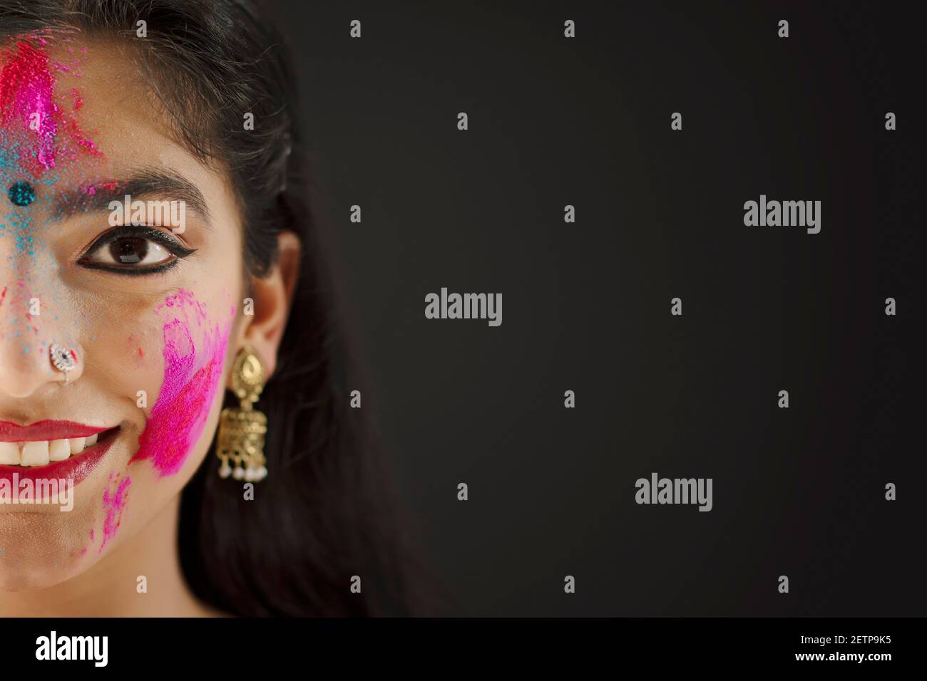 CLOSE SHOT OF ONE SIDE OF A FACE OF A YOUNG WOMAN WITH HOLI COLOURS ON HER Stock Photo