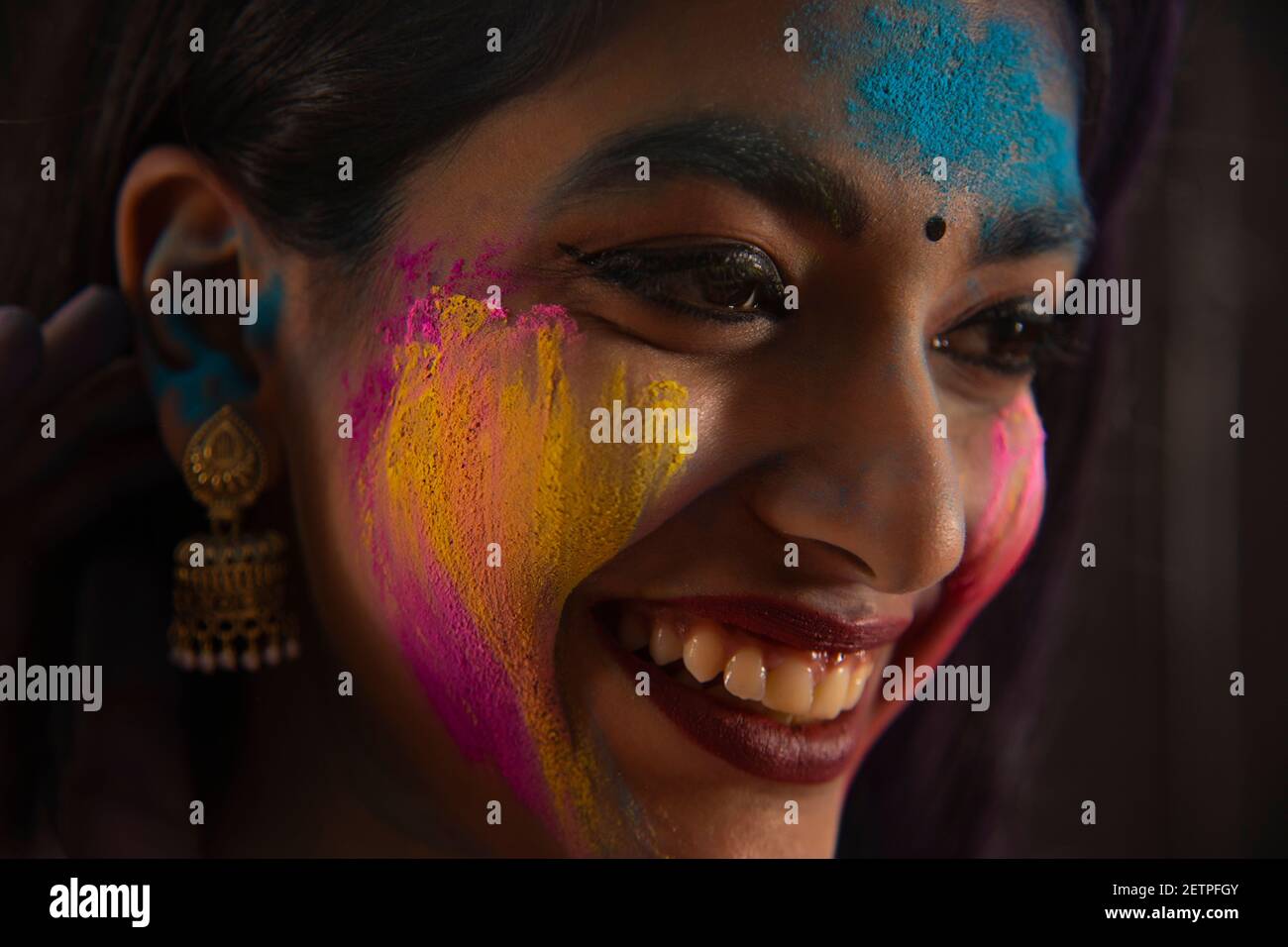 SIDE SHOT OF A HAPPY WOMAN WITH GULAL ON HER FACE Stock Photo