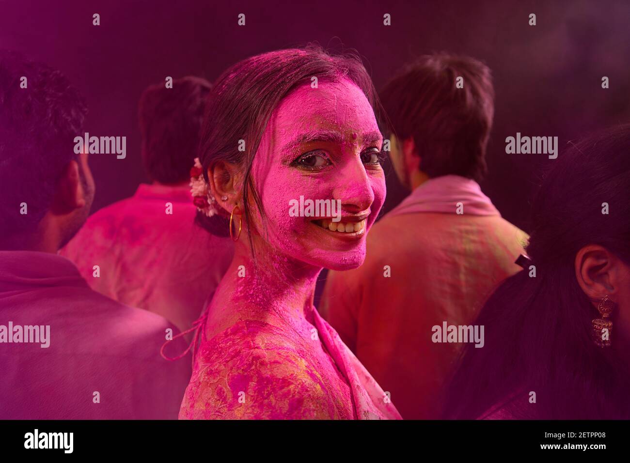 A HAPPY WOMAN WITH GULAL ALL OVER LOOKING AT CAMERA WHILE CELEBRATING HOLI Stock Photo