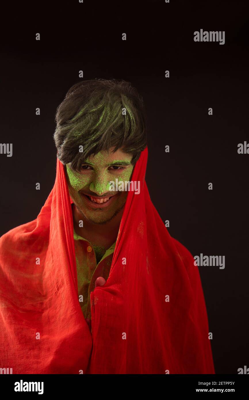 A YOUNG MAN WITH GULAL ON HIS FACE PLAYFULLY STANDING WITH DUPATTA IN HAND Stock Photo