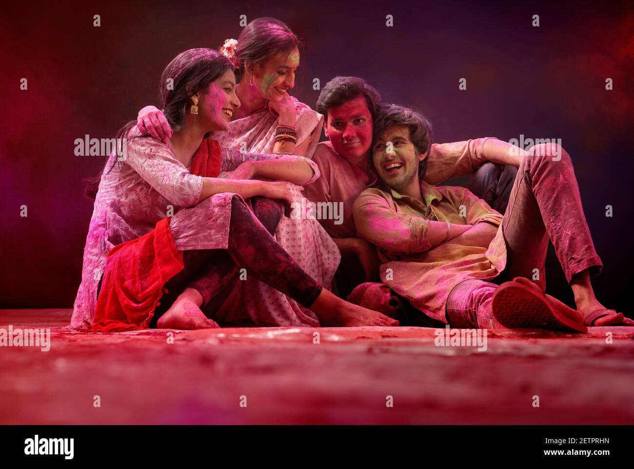A HAPPY GROUP OF FRIENDS SITTING TOGETHER AND ENJOYING HOLI FESTIVAL Stock Photo