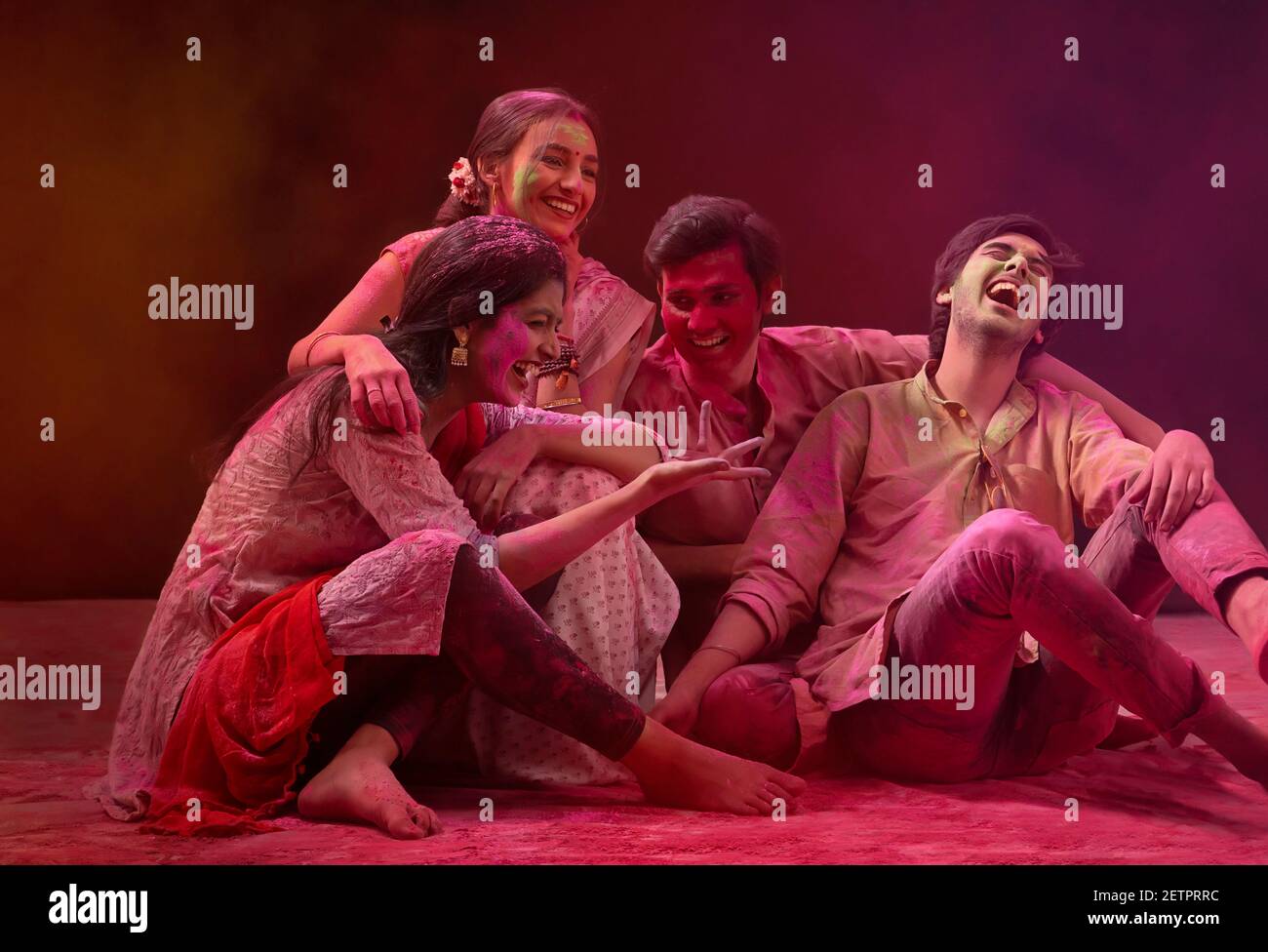 A GROUP OF HAPPY FRIENDS SITTING TOGETHER AND ENJOYING HOLI CELEBRATIONS Stock Photo