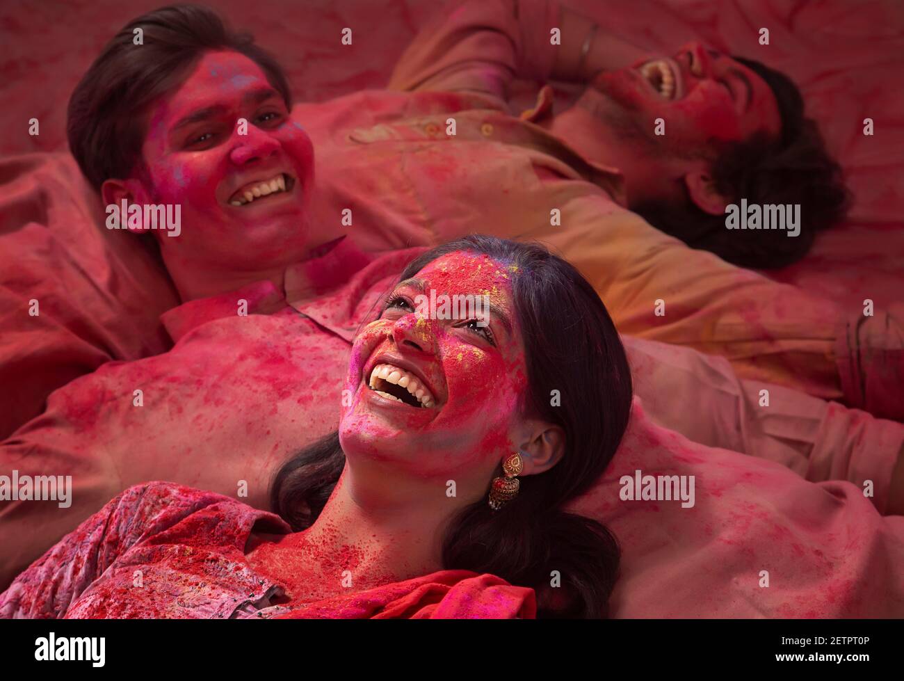 A HAPPY BUNCH OF FRIENDS WITH GULAL ALL OVER LYING ON EACH OTHER DURING HOLI Stock Photo