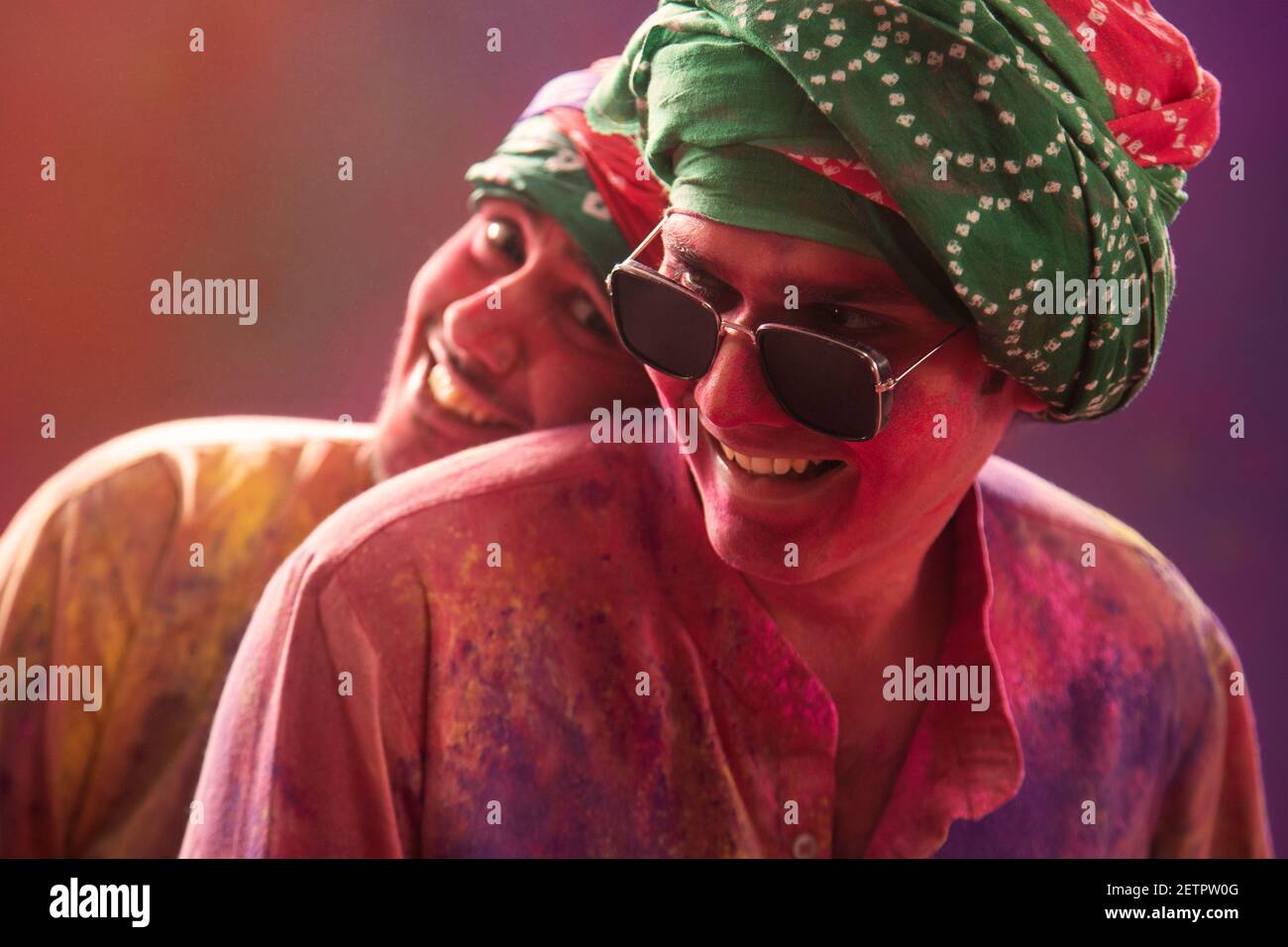 CLOSE SHOT OF TWO YOUNG MEN WITH HOLI COLOURS ALL OVER THEM SITTING TOGETHER HAPPILY Stock Photo