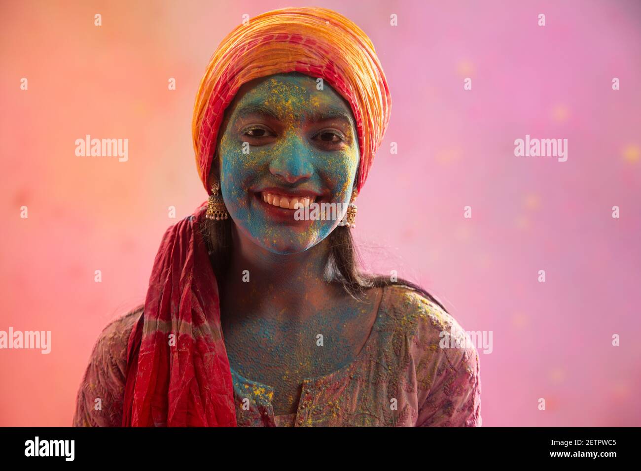 PORTRAIT OF A SMILING YOUNG WOMAN WITH GULAL ALL OVER WEARING PAGDI Stock Photo