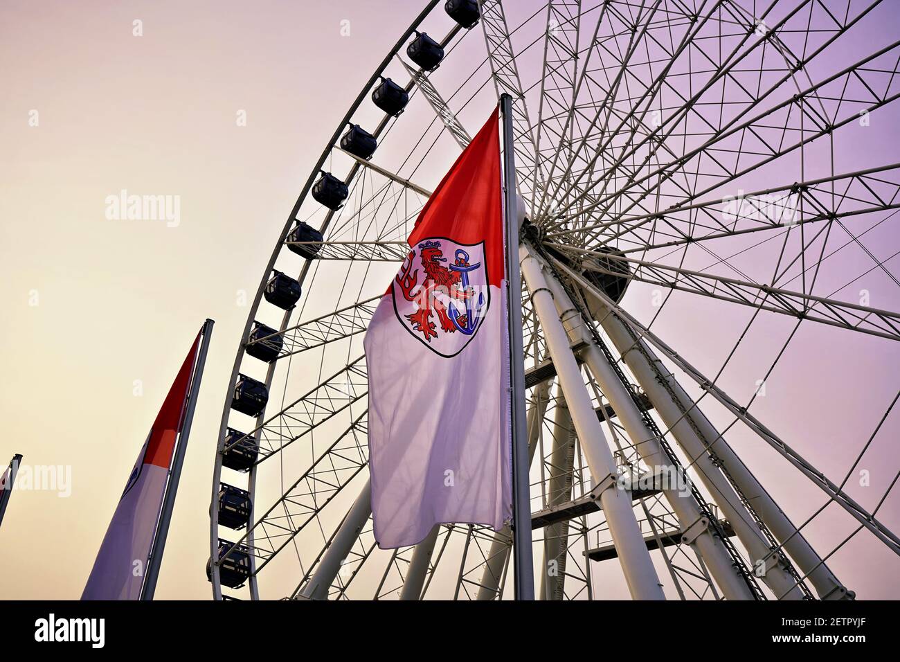 Ferris Wheel at sunset in Düsseldorf Old Town with flag of Northrhine-Westphalia in front. Stock Photo