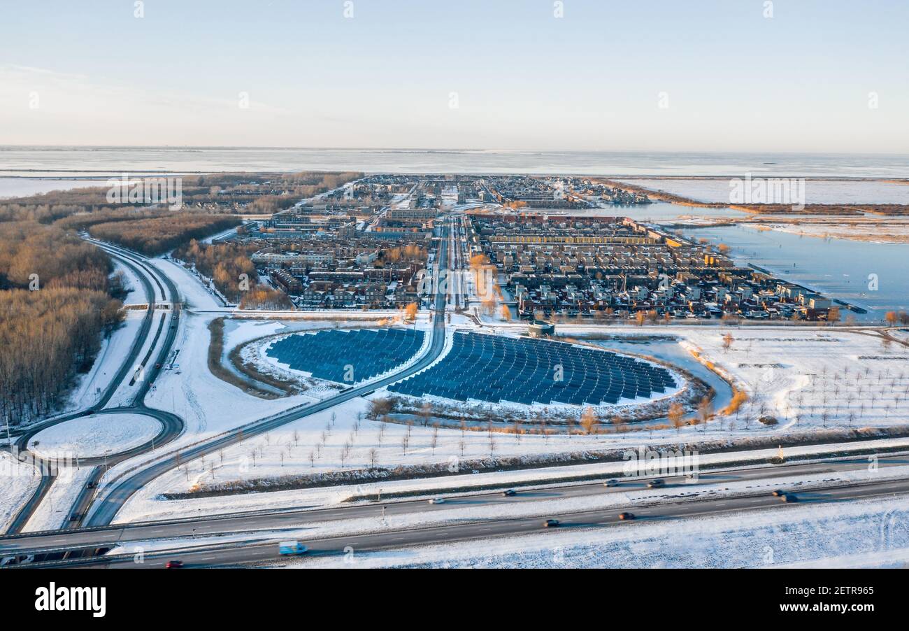Modern sustainable neighbourhood surrounded by nature in Almere, The Netherlands, powered by solar energy. Winter landscape. Aerial shot. Stock Photo