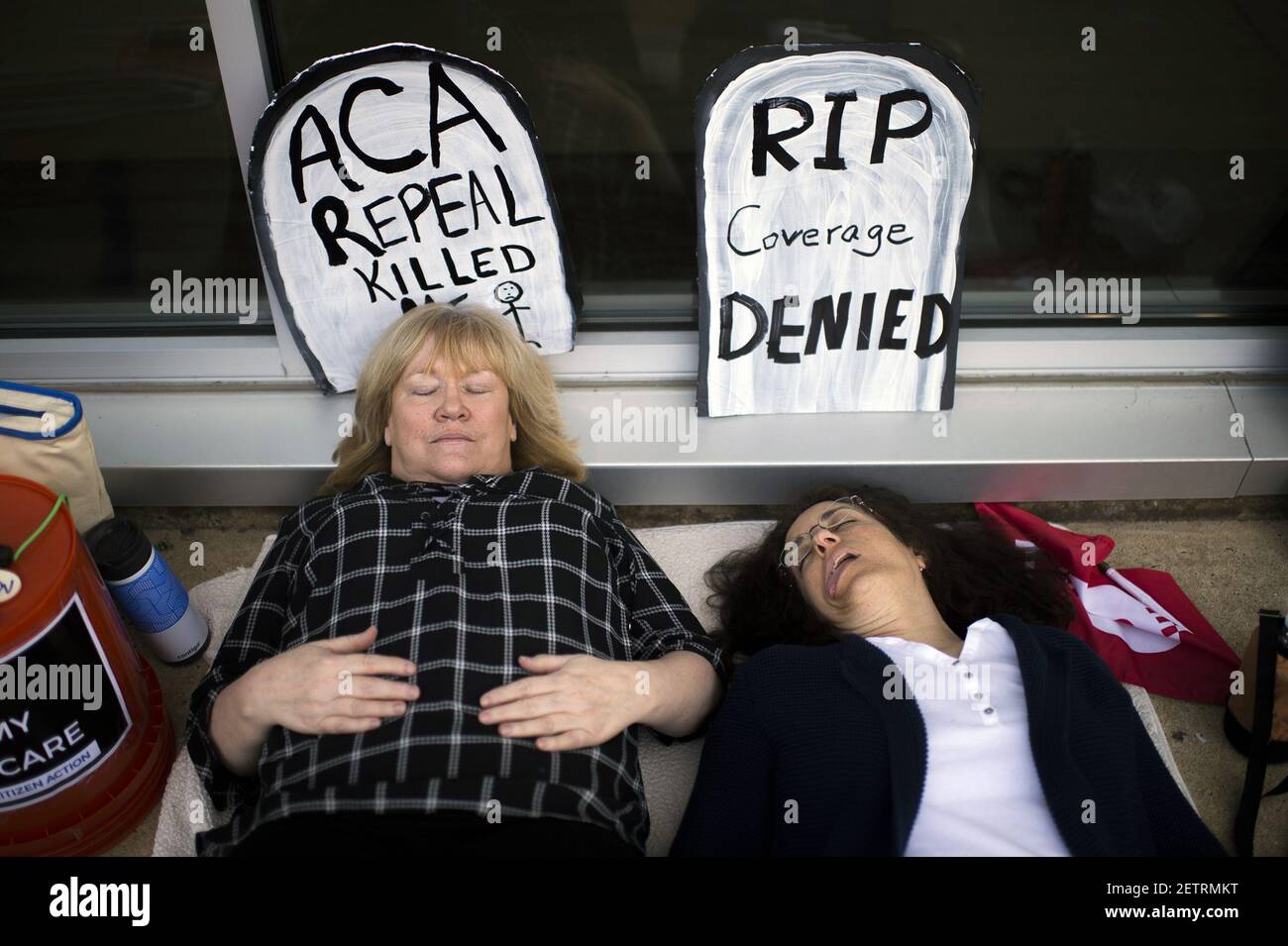 May 10, 2017; Willingboro, NJ, USA; Maureen Quinn of Woodbury (left) and Maria Palmer of West Deptford play dead as protestors gather before a town hall meeting with Congressman Tom MacArthur (R-NJ, not pictured) in Willingboro. Mandatory Credit: Joe Lamberti/Courier-Post via USA TODAY NETWORK *** Please Use Credit from Credit Field *** Stock Photo