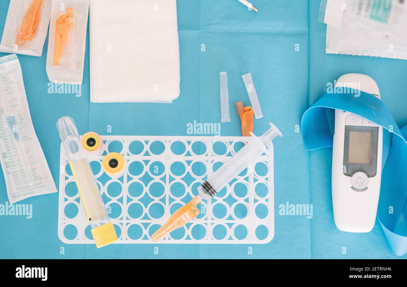 Top view of syringe and flask arranged on table with assorted medical equipment for coronavirus test Stock Photo