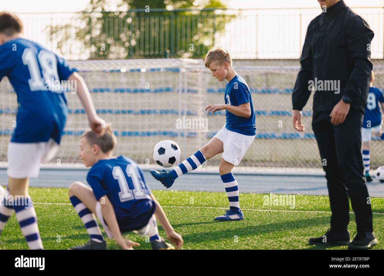 Boy juggling soccer ball. Happy children playing sports on grass turf