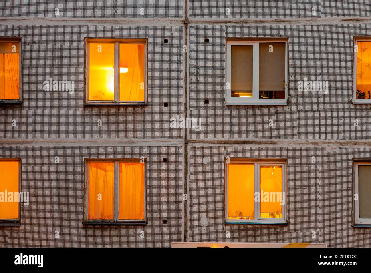 Wall with Iluminated windows of soviet era block apartment building. Stock Photo