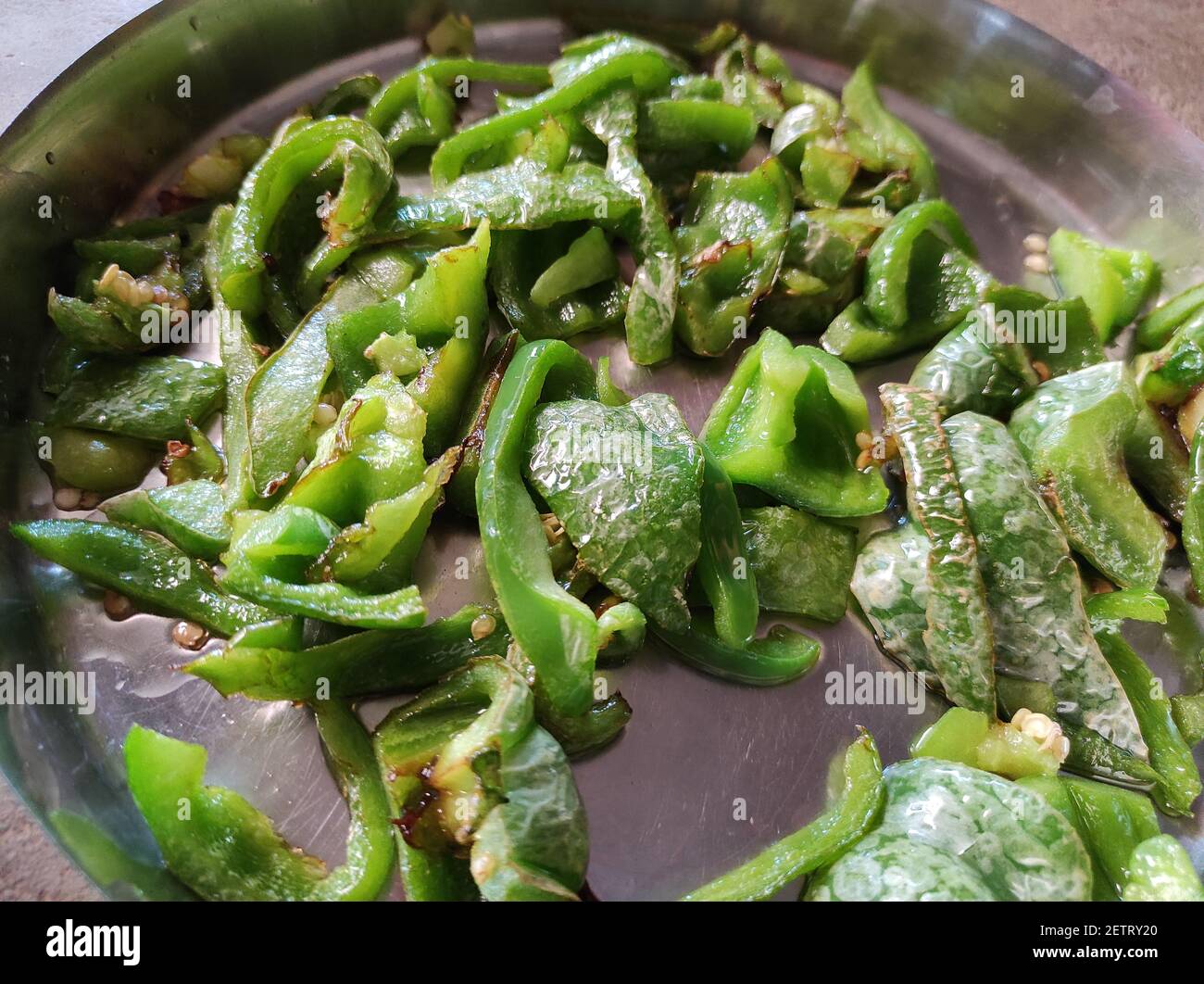 A top view of sliced green chili peppers in a frying pan Stock Photo ...