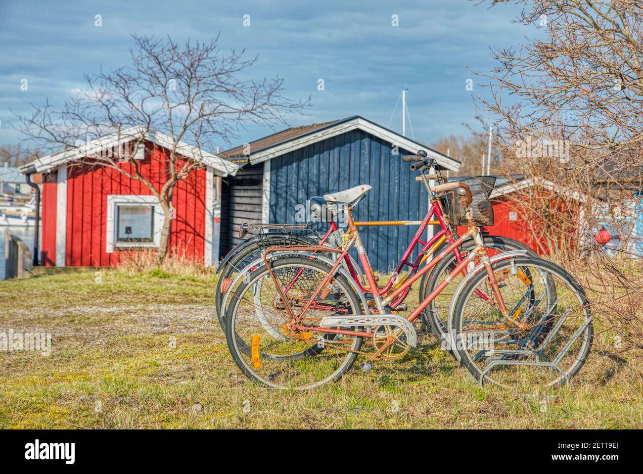 Lone old bicycle forgotten in a rack in a holiday or vacation village. Red abandoned rusty bicycles provide an illustration of Scandinavian lifestyle Stock Photo