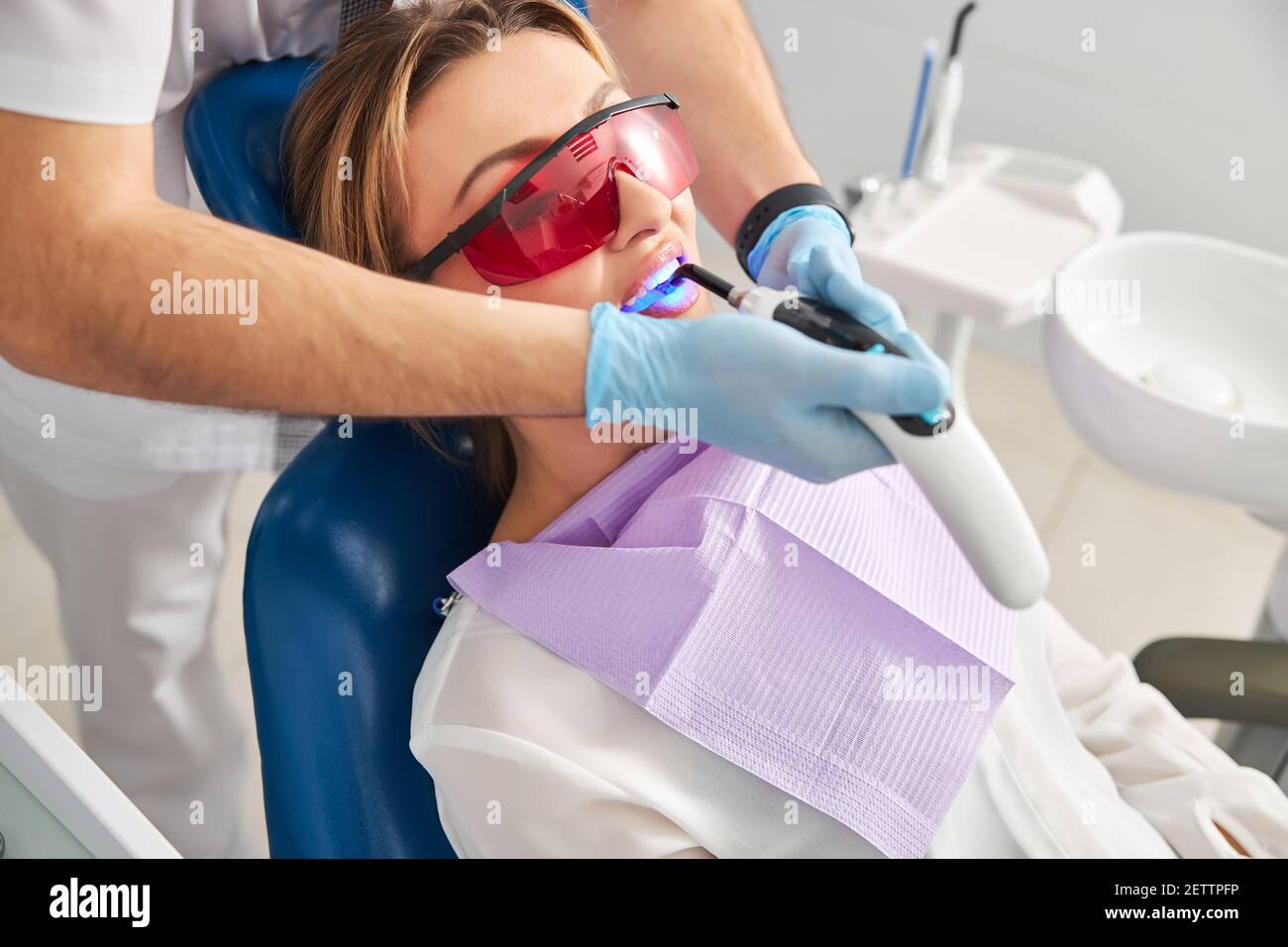 Dentist employing dental curing light on a woman patient Stock Photo