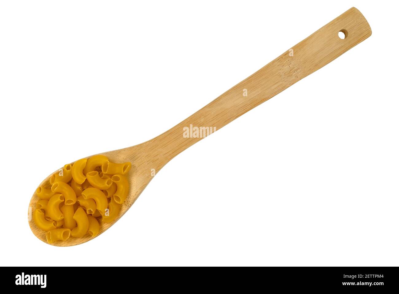 Top view of a portion of organic elbow macaroni on a wood kitchen spoon isolated on a white background. Stock Photo