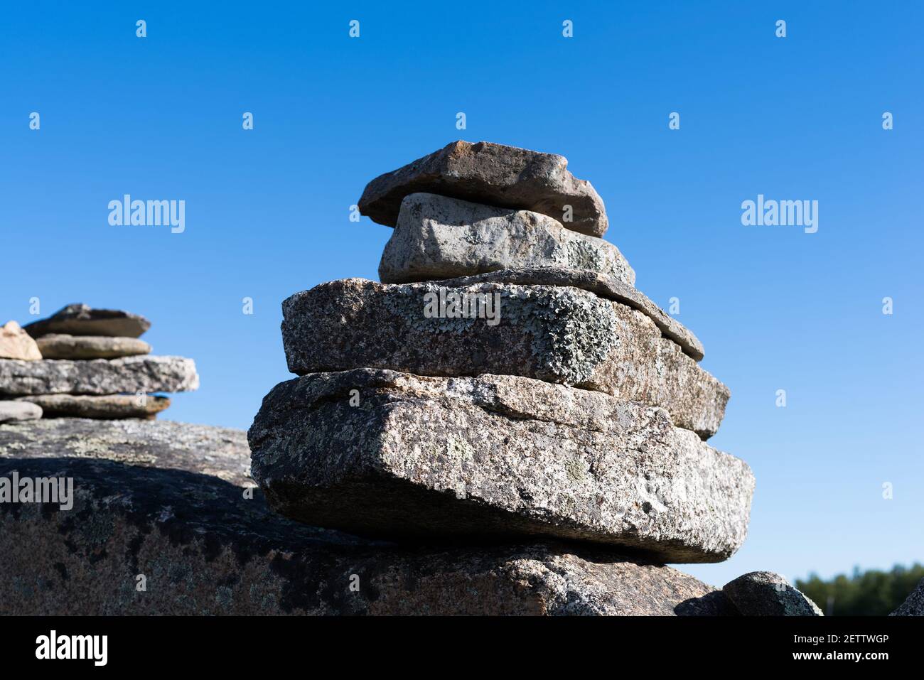 Wide view of two small stacks of rocks on a boulder in the early morning light. Stock Photo