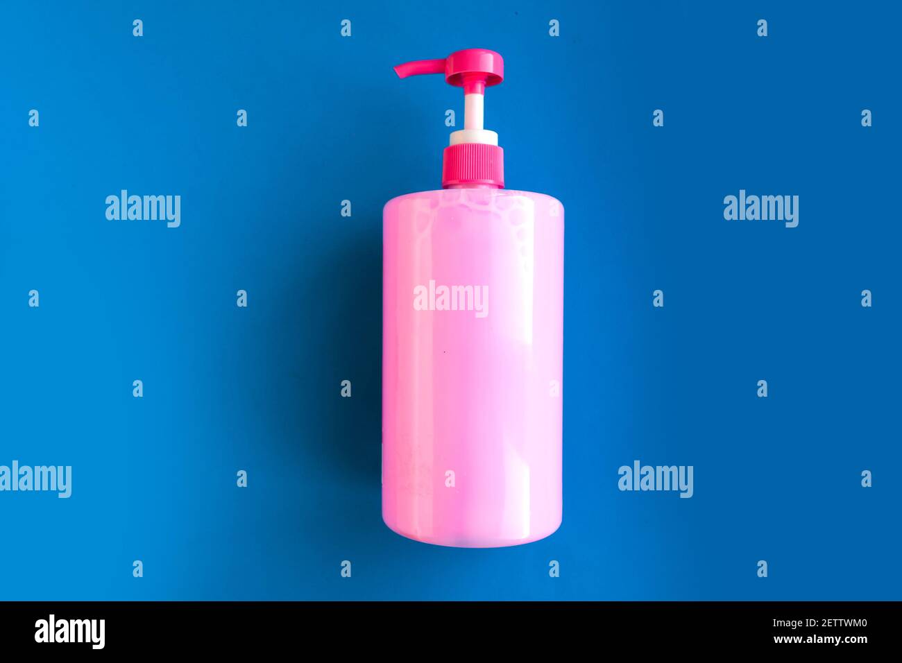 Bottle with pink dishwashing liquid on dark blue background. Minimal
