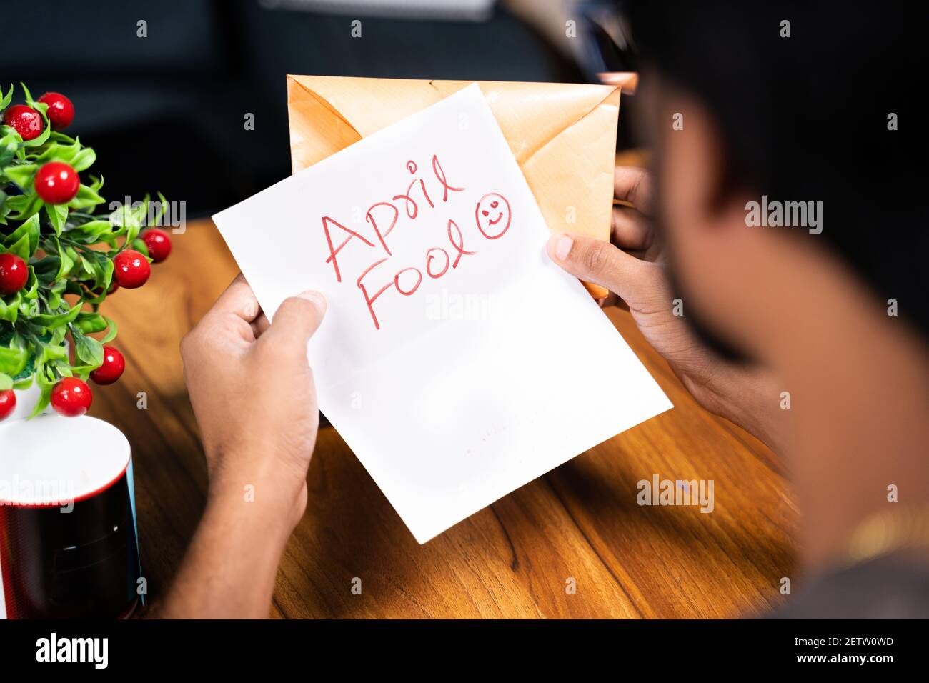 Shoulder shot of young man receiving prank latter - Concept of April fools day prank showing by sending surprise letter, after opening mentioned april Stock Photo