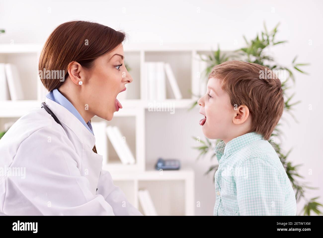 Cute child patient with doctor showing tongue, examination throat Stock