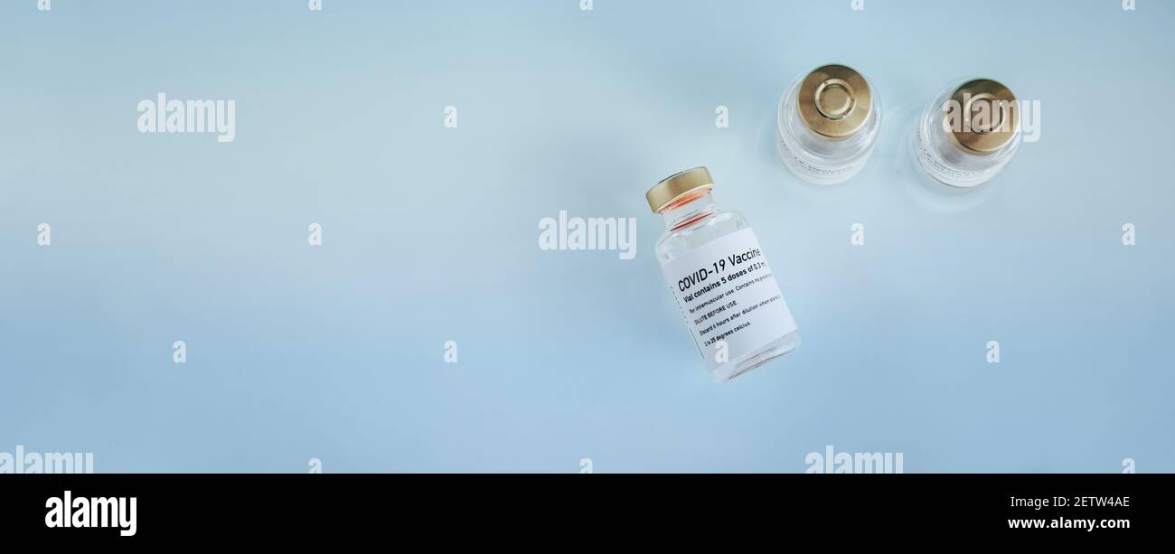 Top view of a three covid-19 vaccine vials on blue background. Banner ...