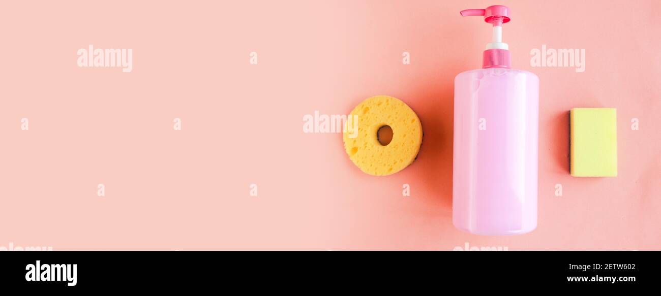 Bottle with pink dishwashing liquid and sponges on pink pastel