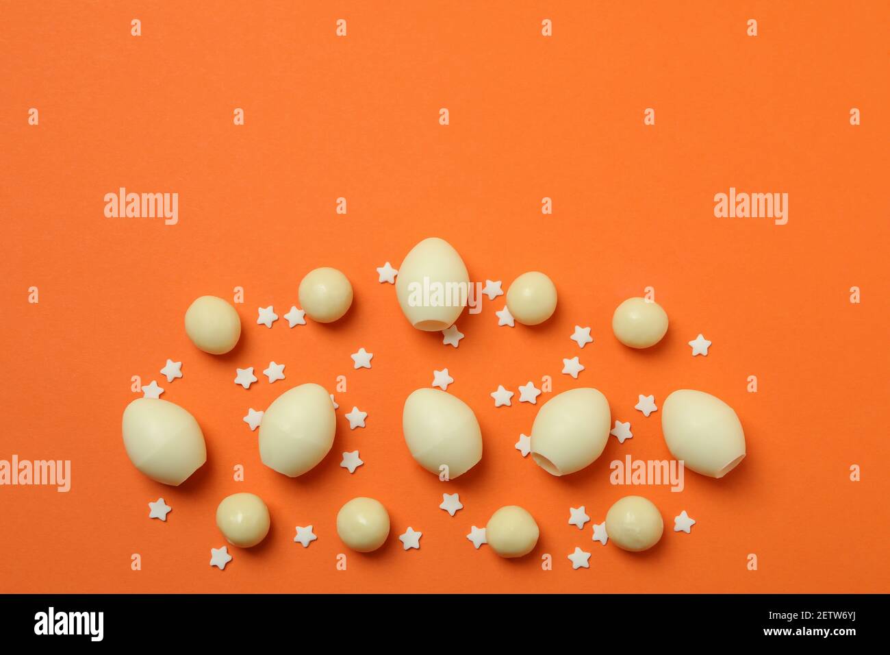 Easter chocolate eggs and sprinkles on orange background Stock Photo
