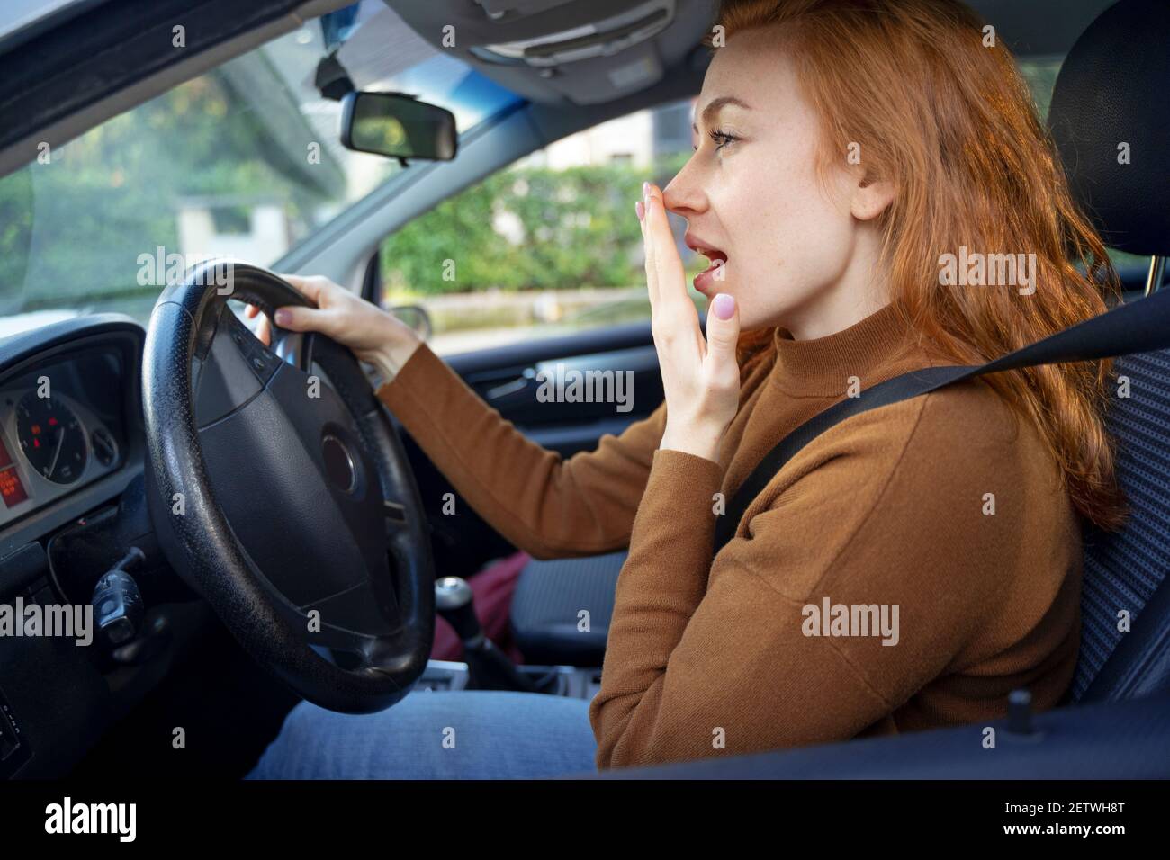 Woman feeling tired while driving her car and yawning Stock Photo Alamy