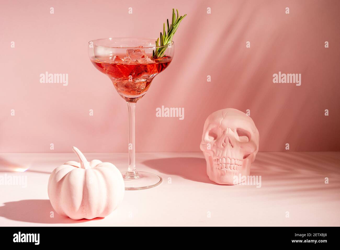 Halloween minimal concept with pink pumpkin, skull and cocktail. Creative holiday party background. Stock Photo