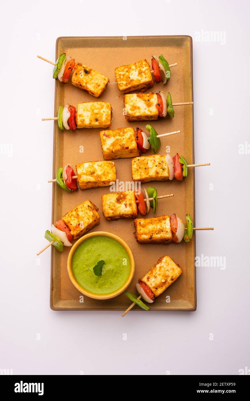 Starter snack Paneer Tikka with stick in plate with green chutney