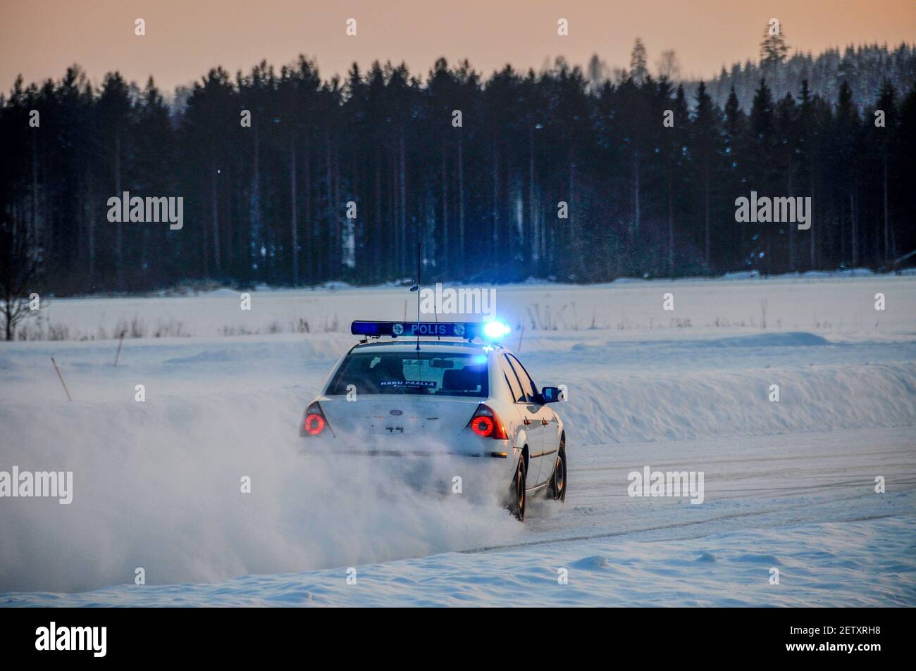Blue lights flashing as a Finnish Traffic Police car speeds along a snow-covered road as part of the snow driving training for the Finnish Traffic Pol Stock Photo