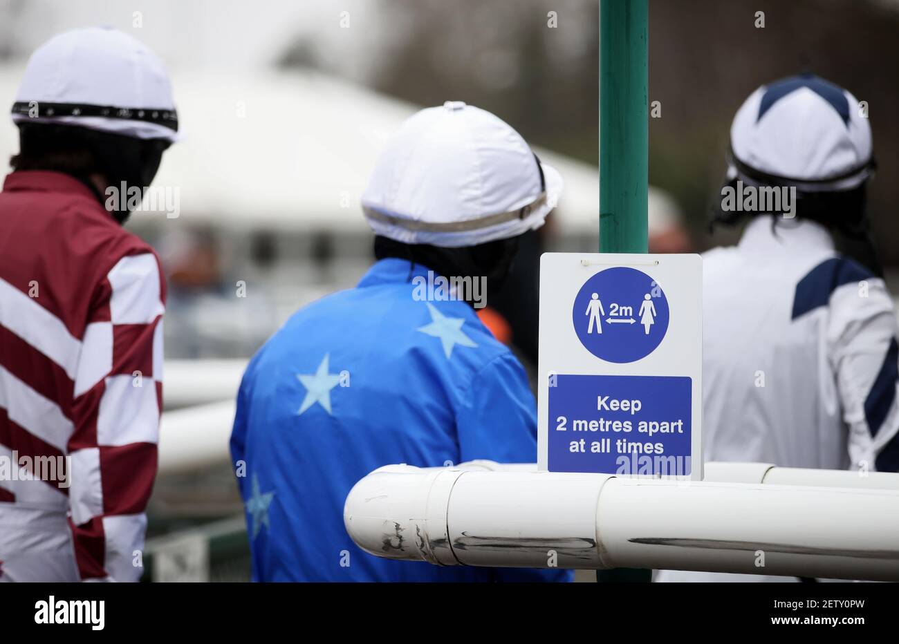 Lorcan Murtagh, Charlie Hammond and Richard Patrick (left-right) walk past a social distancing sign before the first race at Leicester Racecourse. Picture date: Tuesday March 2, 2021. Stock Photo