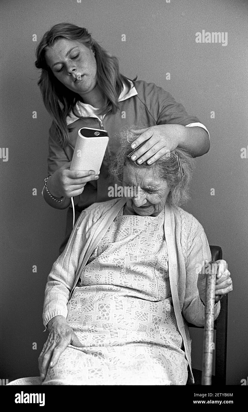 Sixteen year old school girl on work experience as a care assistant in care home. Drying woman hair. Stock Photo