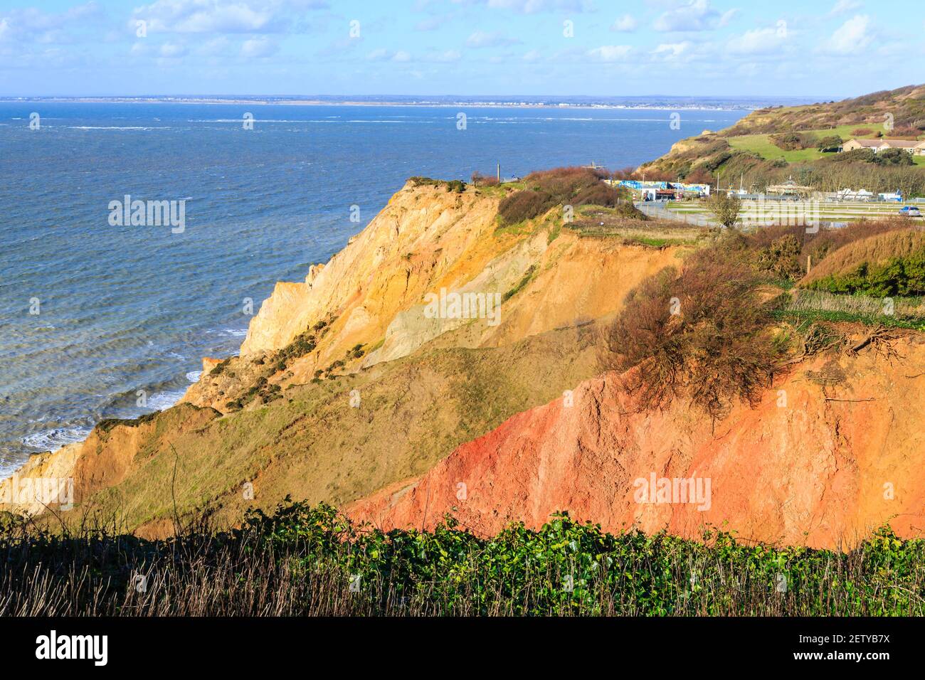 The multi-coloured Eocene sand cliffs of Alum Bay, Isle of Wight, from which sand layer tourist souvenirs are made and view across the Solent Stock Photo