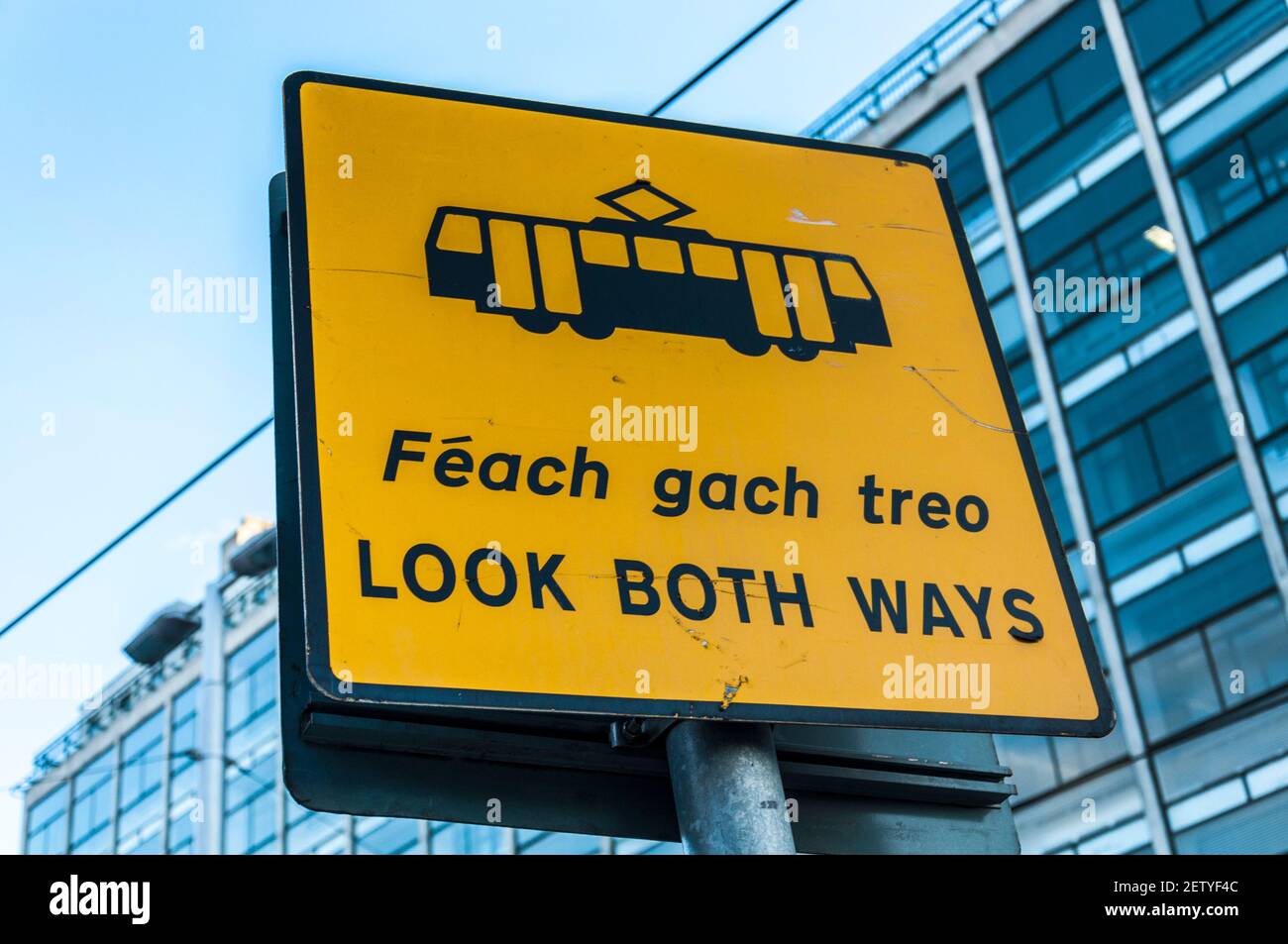 Dublin, Ireland, sign signage LOOK BOTH WAYS in English and Irish Gaelic language. Warning for LUAS tram public transport system in the capital city. Stock Photo