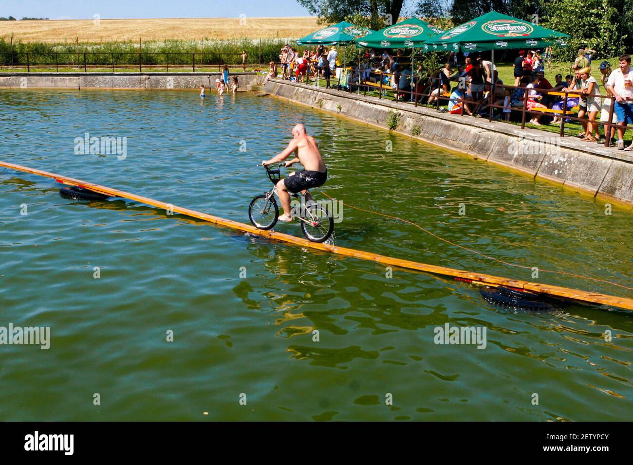 Unusual sports, crossing the water reservoir by bike Czech Republic in summer rural life an annual competition weird sports bicycle crossing the water Stock Photo