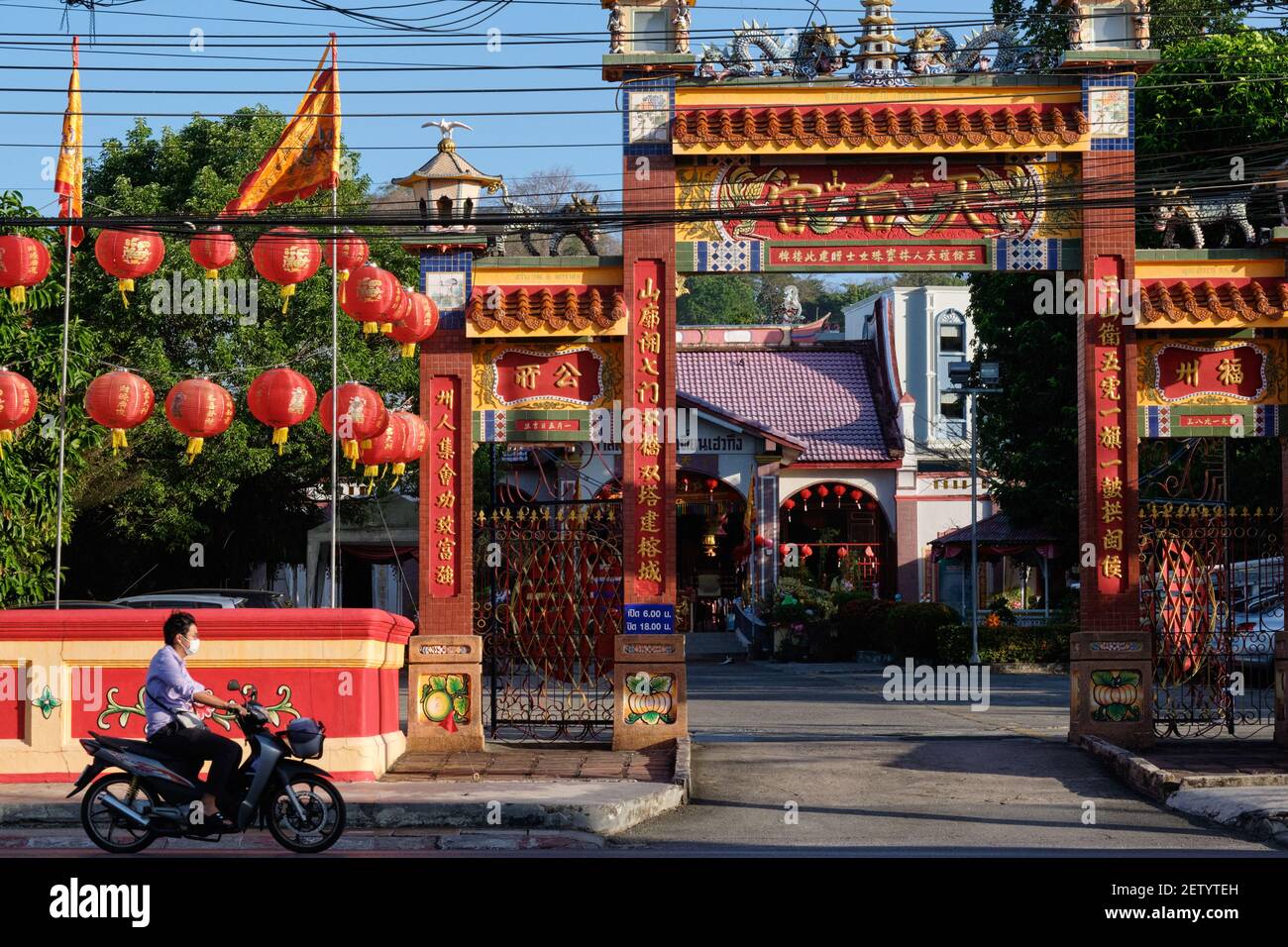A motorcyclist rides past Sam San Tian Huo Geung Shrine (Wat Mae Yanang), a Chinese-style Taoist temple in Krabi Road, Phuket Town, Thailand Stock Photo