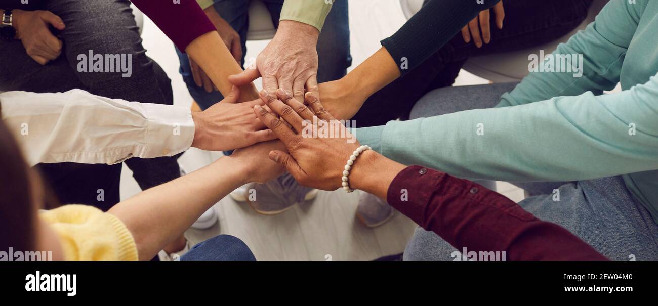 People of different ages fold their hands on each other, symbolizing their unity and support. Stock Photo