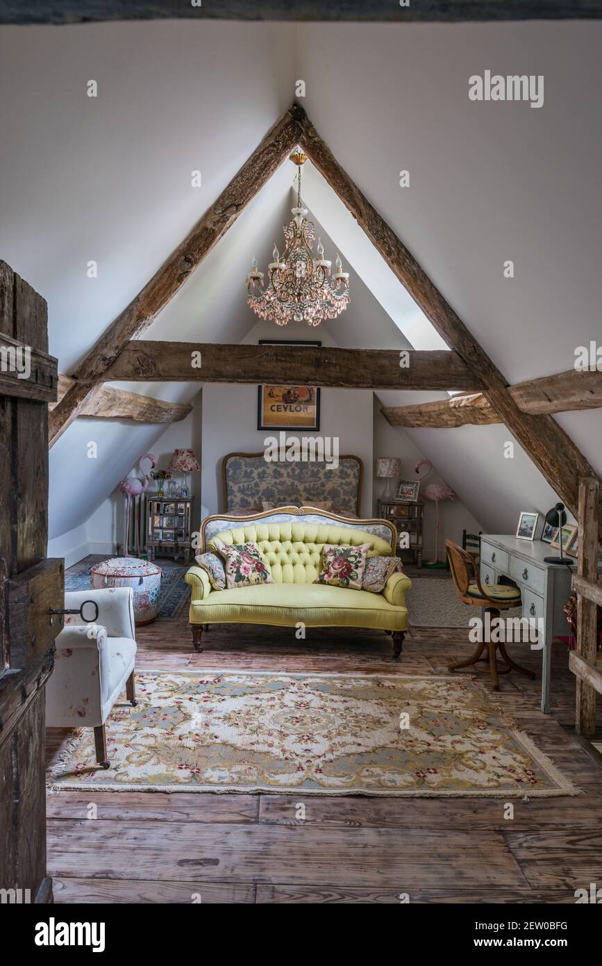 Beamed attic bedroom with buttoned sofa and toile headboard in 17th century Dorest farmhouse. Stock Photo