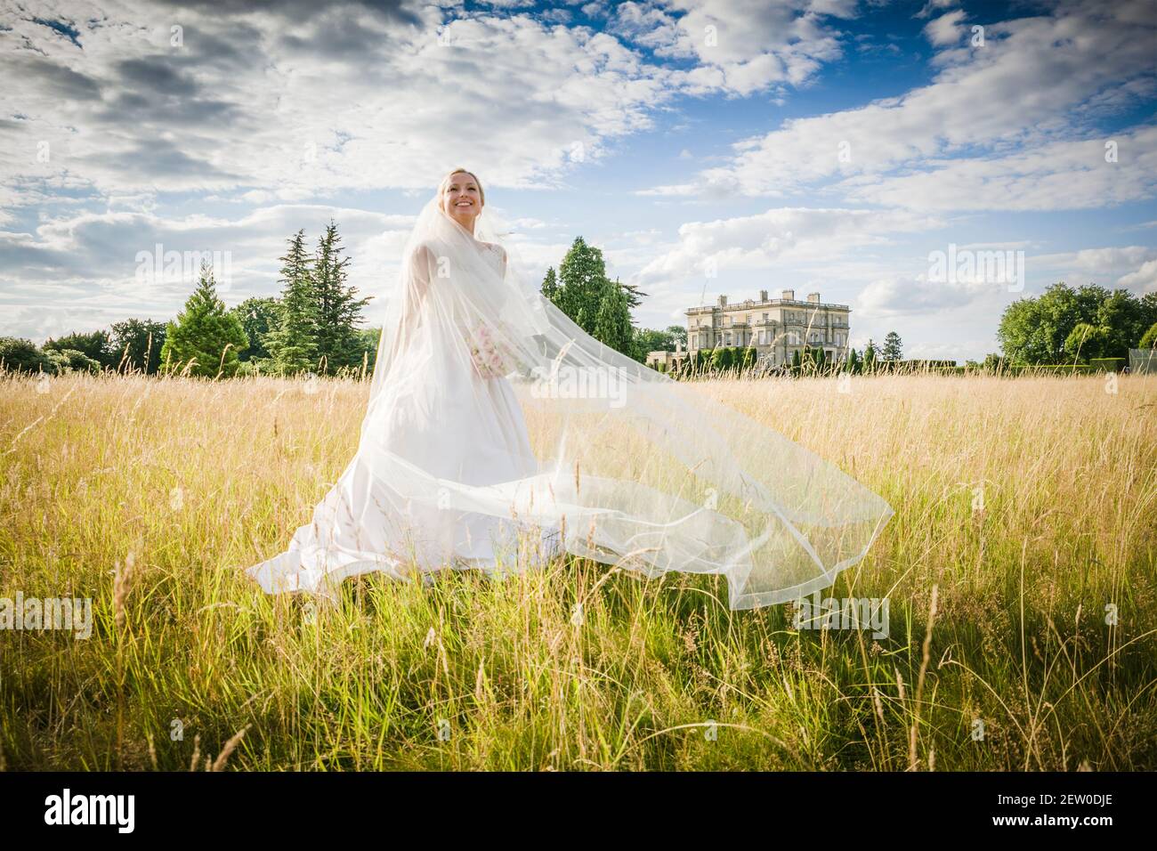 Bride standing in long grass field smiling with happiness Stock Photo