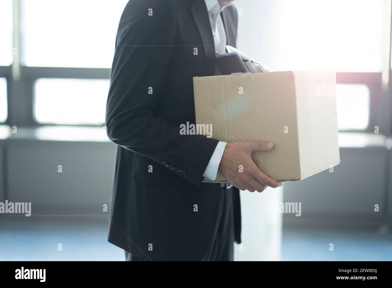 Fired businessman carrying box of personal items Stock Photo