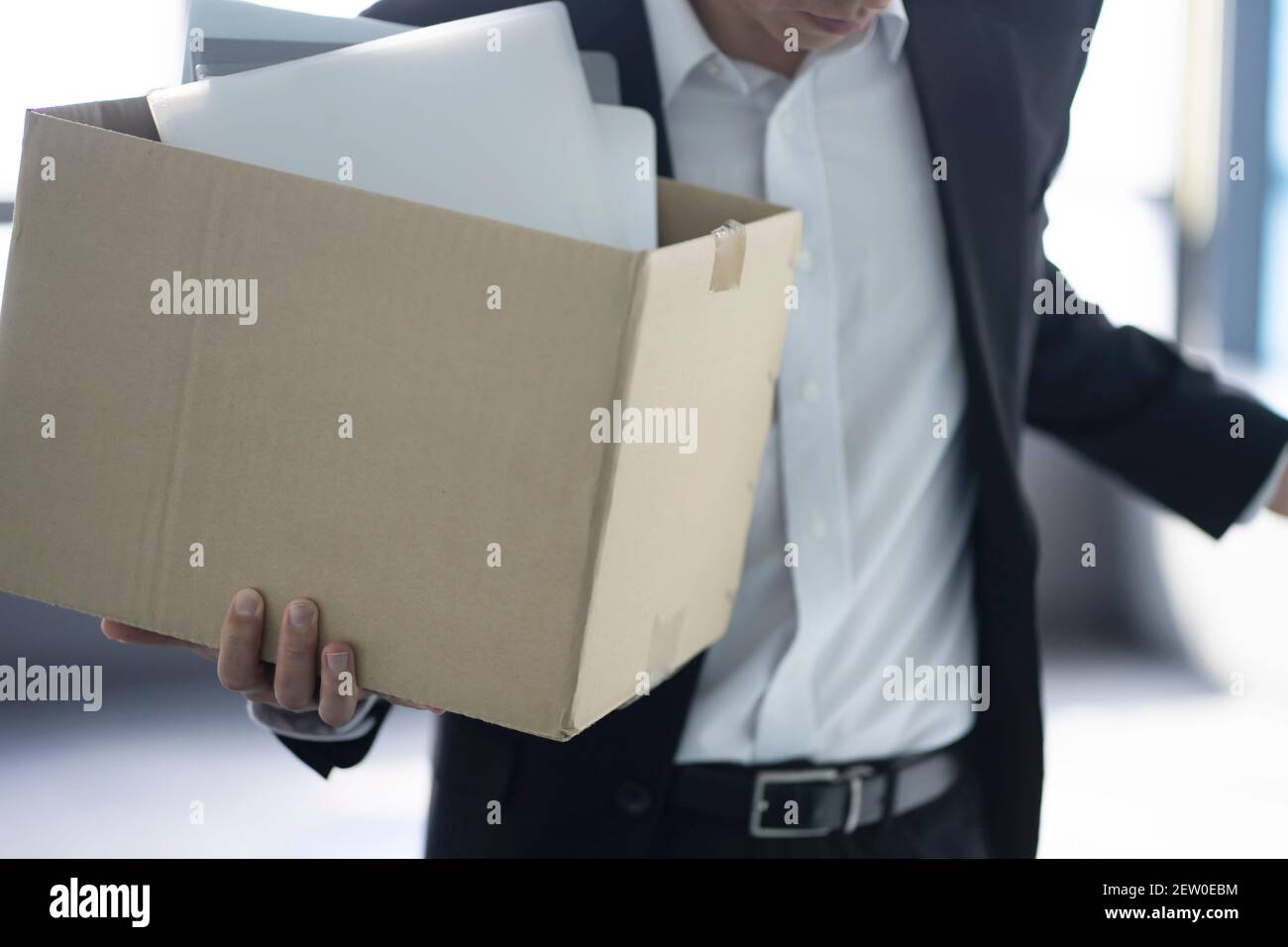 Fired businessman carrying box of personal items Stock Photo