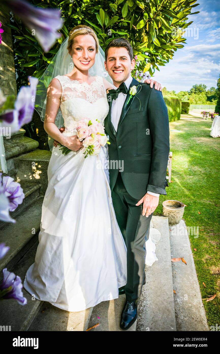 Bride and Bridegroom just married standing on the stone steps in the grounds of a mansion house. Stock Photo