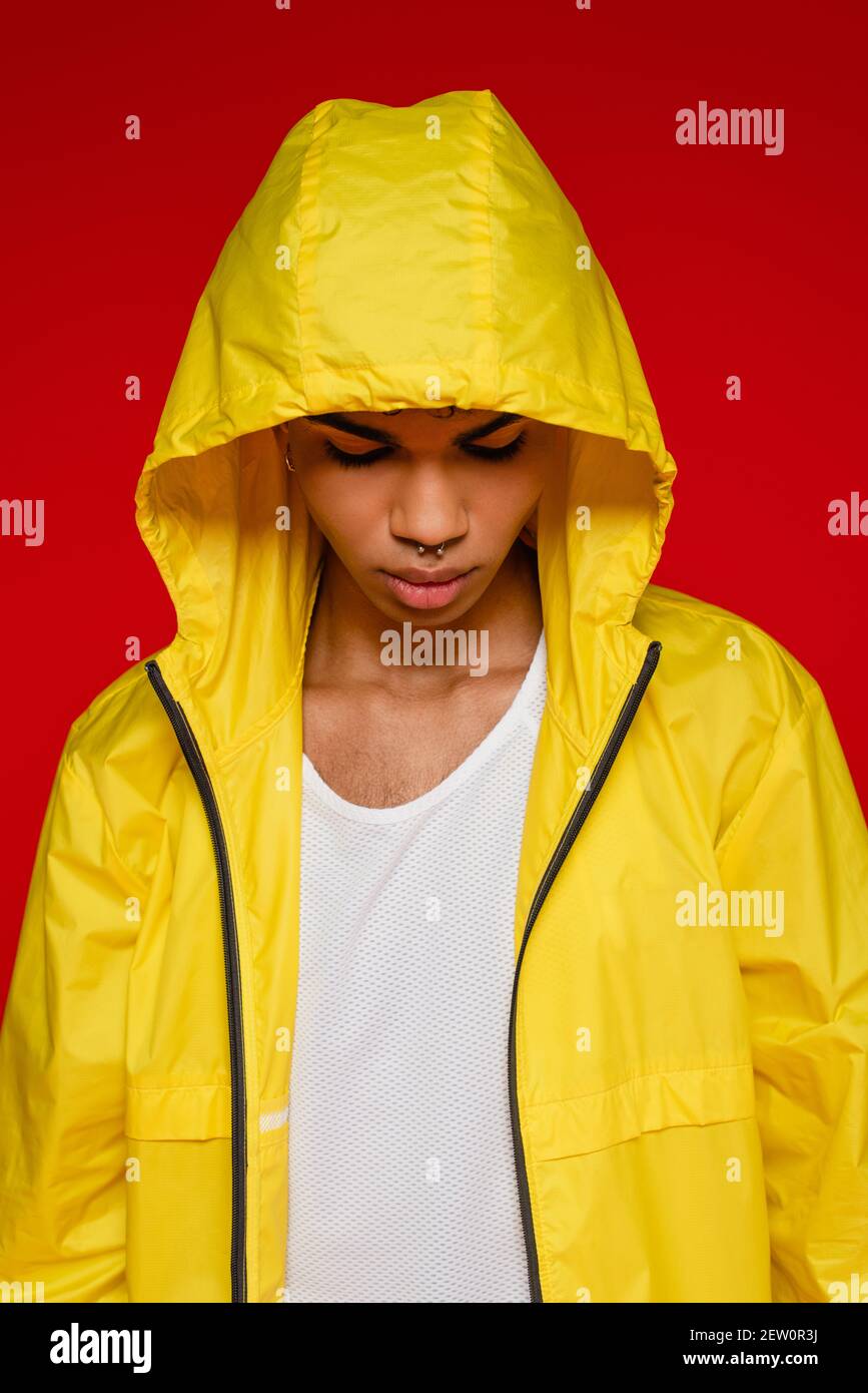 stylish african american man in yellow rain jacket with hood isolated on red Stock Photo