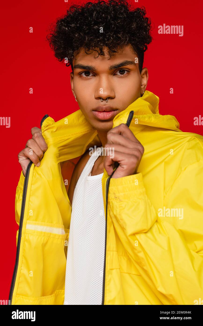 stylish african american man in yellow rain jacket isolated on red Stock Photo