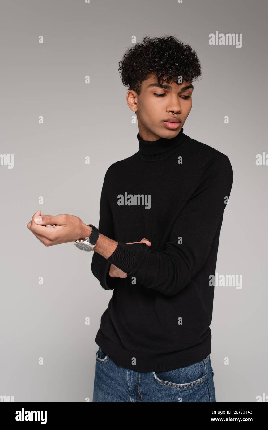 young african american man adjusting sleeve on turtleneck sweater isolated on grey Stock Photo