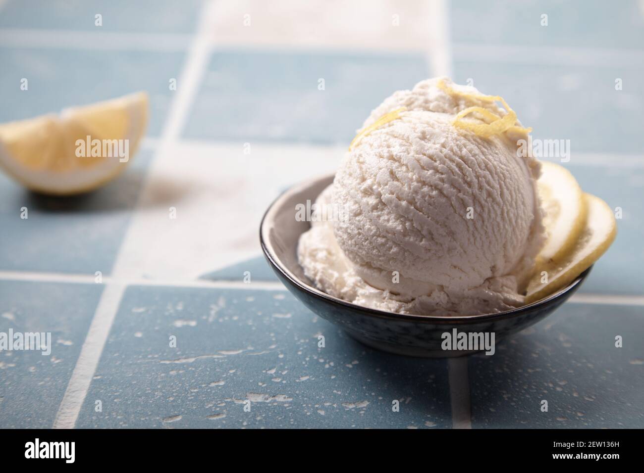 Delicious gelato scoop with ripe citrus fruit slices and lemon zest on top on tiled surface Stock Photo